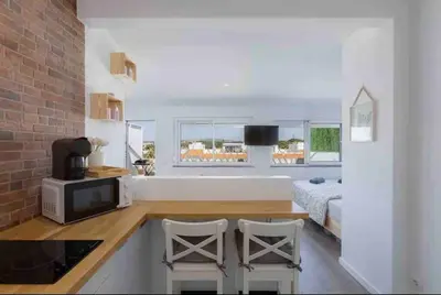 a kitchen with a counter with a microwave and a bed at Cozy studio near the beach in Quarteira