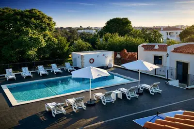 a swimming pool with chairs and umbrellas on a roof at Mourisca by Check-in Portugal in Vilamoura