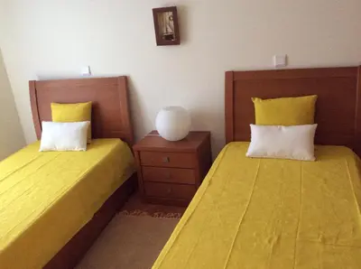 two beds in a room with yellow sheets and yellow pillows at Vila Bairos Apartment Vilamoura in Vilamoura