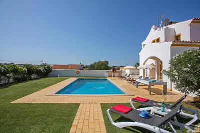 a villa with a swimming pool and two lawn chairs at Villa Carlos by Villa Plus in Galé