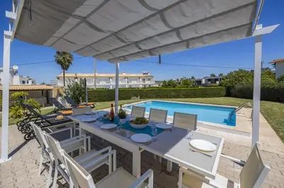 a patio with a table and chairs and a swimming pool at Villa Casa Duarte by Villa Plus in Olhos de Água