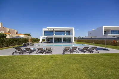a group of chairs and a pool in front of a house at Villa Casa Gardenia by Villa Plus in Galé