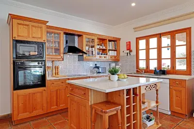 a kitchen with wooden cabinets and a stove top oven at Quinta Boliqueime by Portucasa in Boliqueime