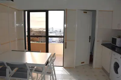 a kitchen with a table and chairs and a window at Blife Chelsya private rooms in Faro