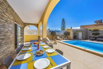 a dining table with chairs next to a swimming pool at Villa Graca by Villa Plus in Albufeira