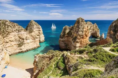 a sailboat in the ocean between some rocks at White Studio - Ocean View in Albufeira
