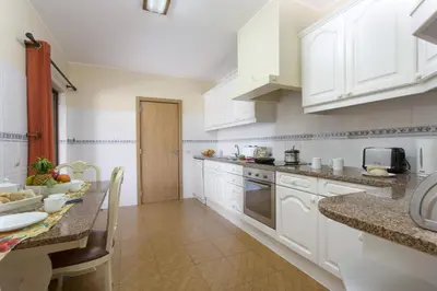 a kitchen with white cabinets and a table in it at Villa Lurdes by Villa Plus in Galé