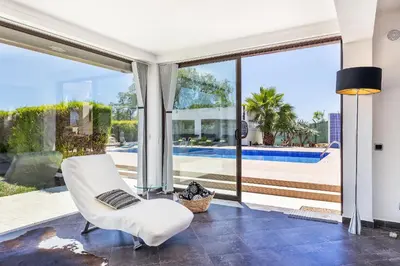 a living room with a white chair and large windows at Loendros, Calma Moradia com Piscina Privada, Guia in Guia