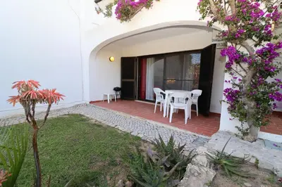 a patio with a table and chairs and flowers at Studio Camélia 68 at São Rafael Beach - Albufeira in Albufeira