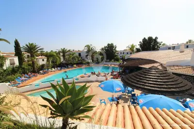a view of a swimming pool with blue umbrellas at Studio Camélia 68 at São Rafael Beach - Albufeira in Albufeira
