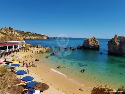 a beach with umbrellas and people in the water at Studio Camélia 68 at São Rafael Beach - Albufeira in Albufeira