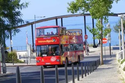 a red double decker bus driving down a street at Espaçoso apt T2, em Olhos Agua in Albufeira
