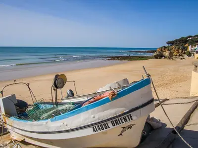 a boat sitting on the beach next to a beach at Espaçoso apt T2, em Olhos Agua in Albufeira