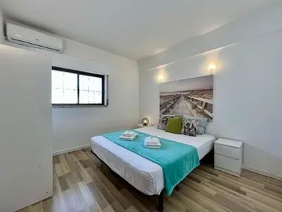 a bedroom with a bed with a blue blanket at Albufeira Central 7 by Homing in Albufeira
