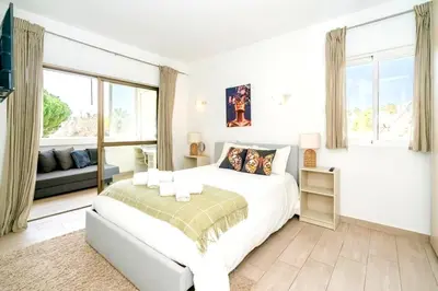 a white bedroom with a bed and a window at Spacious 1 bed in Vilamoura, Fast Wifi & Pool in Quarteira