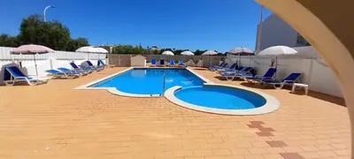 a swimming pool with blue chairs and umbrellas at Apartamento T1 todo equipado in Albufeira