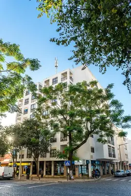a white building with a tree in front of it at HostWise - Spacious & Sunny Flat - Loulé in Loulé