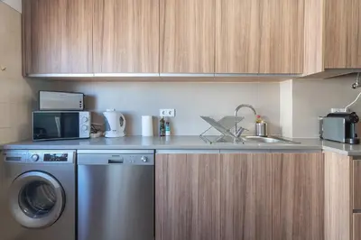 a kitchen with a washing machine and a sink at HostWise - Spacious & Sunny Flat - Loulé in Loulé