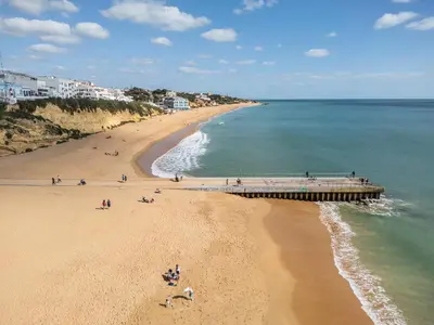 a beach with people on the sand and a pier at Phenthouse Monaco - Jacuzzi - City Center - Sea View in Albufeira