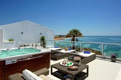 a patio with a hot tub on a balcony with the ocean at Casa Chanel - Ocean front with rooftop SPA Jacuzzi in Albufeira