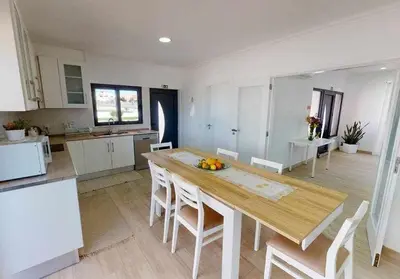 a large kitchen with a wooden table and chairs at Villa Malmequer by FHR private in Quarteira