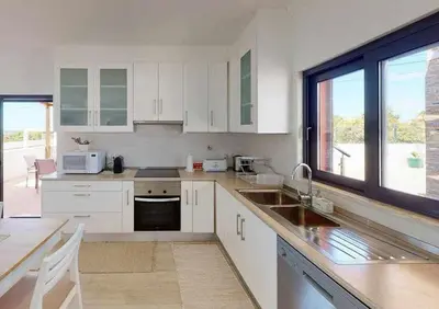 a kitchen with white cabinets and a large window at Villa Malmequer by FHR private in Quarteira