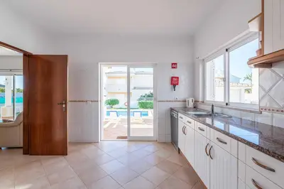 a kitchen with white cabinets and a view of a pool at Villa Sofy in Galé