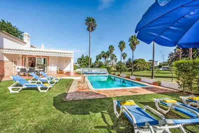 a backyard with a swimming pool with chairs and an umbrella at Casa Lorena in Guia