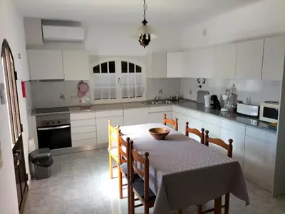 a kitchen with a table and chairs and a kitchen with white cabinets at Vivenda Atanázio By Férias com Sol in Loulé
