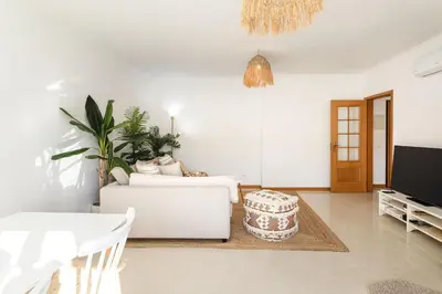 a living room with a white couch and a tv at Modern 1BR Apartment in Central Albufeira with Balcony & Parking, by Hopstays in Albufeira