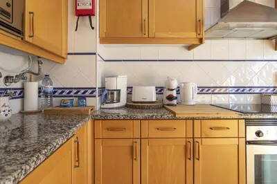 a kitchen with wooden cabinets and a counter top at Modern 1BR Apartment in Central Albufeira with Balcony & Parking, by Hopstays in Albufeira