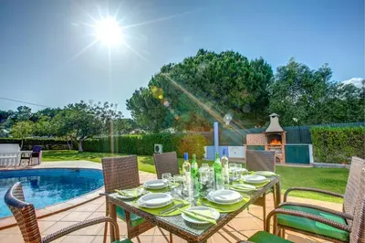 a dining table with chairs next to a pool at Villa Sandra by Villa Plus in Olhos de Água