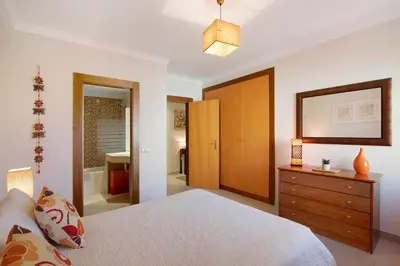 a bedroom with a bed and a dresser and a bathroom at Condomínio Quinta do Vale in Guia