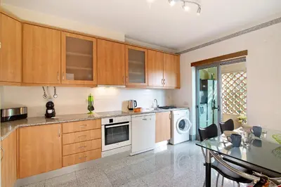 a kitchen with wooden cabinets and a table in it at Condomínio Quinta do Vale in Guia