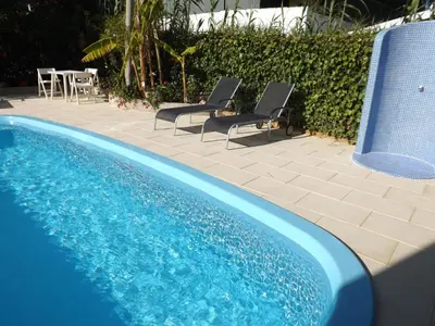 a blue swimming pool with two chairs and a table at Casa Pinheiromar in Albufeira