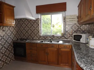 a kitchen with wooden cabinets and a sink and a window at Casa Pinheiromar in Albufeira