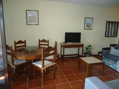 a living room with a table and chairs and a tv at V2 Vilar Jardim Piscina wifi in Quarteira