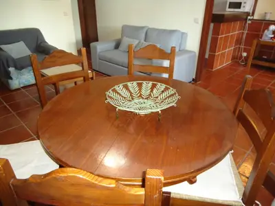 a wooden table with chairs and a couch in a living room at V2 Vilar Jardim Piscina wifi in Quarteira