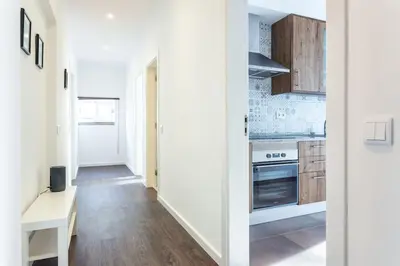 a kitchen with white walls and wooden cabinets at Blife Farensya private rooms near train station in Faro