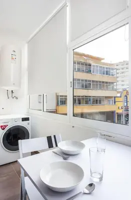 a white kitchen with a table and a window at Blife Farensya private rooms near train station in Faro