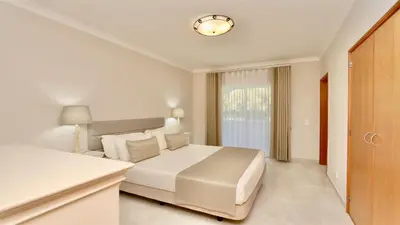 a white bedroom with a bed and a window at Green Valley 05, Cleverdetails, Sleeps 6 adults and 2 children, 4 salted water pools in Vilamoura