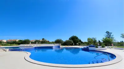 a large pool with blue water in a courtyard at Green Valley 05, Cleverdetails, Sleeps 6 adults and 2 children, 4 salted water pools in Vilamoura
