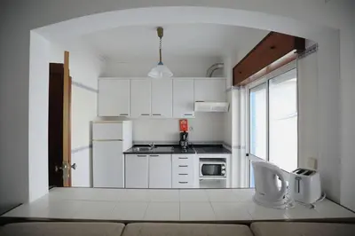 a small kitchen with white cabinets and a window at STUDIO COMPLETO PARA 2 PESSOAS in Albufeira
