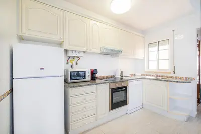 a kitchen with white cabinets and a refrigerator at Notre Damme Apartment in Albufeira