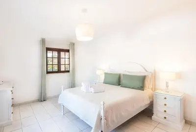 a white bedroom with a bed and a window at Villa Guerreiro in Albufeira