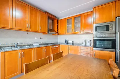 a kitchen with wooden cabinets and a wooden table at Villa Adriana in Albufeira