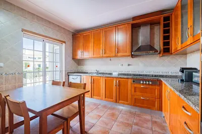 a kitchen with wooden cabinets and a table and chairs at Villa Adriana in Albufeira
