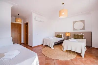 a white room with two beds and a rug at Villa Adriana in Albufeira