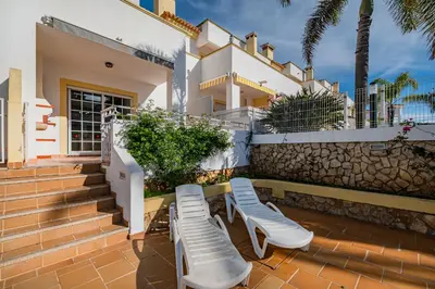 a patio with two chairs and a house at Villa Adriana in Albufeira