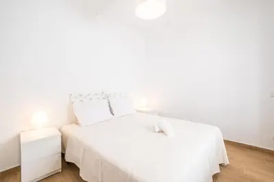a white bedroom with a white bed and a white nightstand at SERAFIM BEACH APARTMENT - Heart of the Old Town in Albufeira